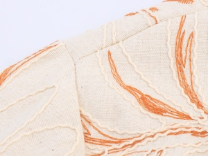 Detailed embroidery on beige cotton linen fabric with floral patterns and fine stitching