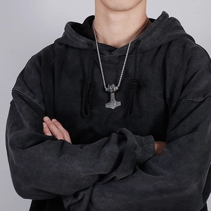 Detailed close-up of a silver Thor's hammer pendant on a necklace worn by a model