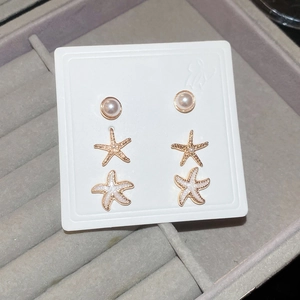 Detail of 6-piece starfish and pearl stud earring set on display card in jewelry tray