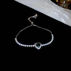 Detail of adjustable silver bracelet featuring a green heart zircon and pavé setting
