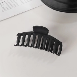 Vue détaillée d'une grande pince à cheveux noire mate pour queue de cheval sur fond blanc