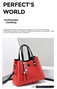 Détail du sac à main rouge texture litchi avec anses noires et breloque en cœur