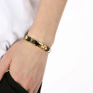 Détail du bracelet magnétique bicolore noir et or en acier tungstène au poignet