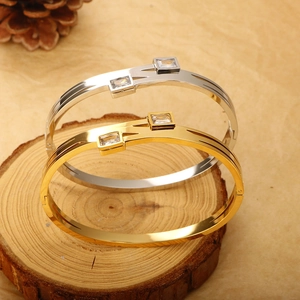 Polished 18K gold and silver steel bangles with square zircon on wood slice