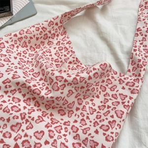 Close-up of heart-shaped leopard print on off-white canvas shoulder bag