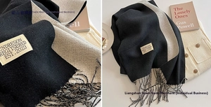 Detail of double-sided cashmere-like scarf with fringe edges and woven brand label