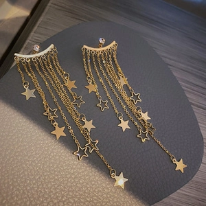 Detailed view of gold tassel earrings with hanging chains and delicate star pendants
