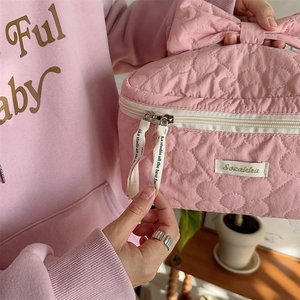 Détail de la trousse à maquillage matelassée rose avec poignée nœud et ruban zippé