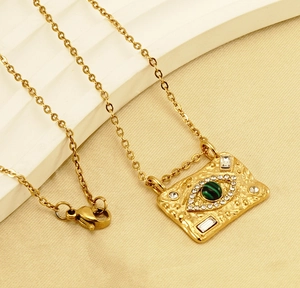 Macro detail of 18K gold necklace featuring malachite evil eye and sparkling crystals