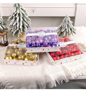 Drei Boxen mit lila, goldenen und roten Weihnachtskugeln auf einer gemütlichen weißen Decke