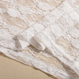 Macro shot of white floral lace fabric showing delicate hollow embroidery details