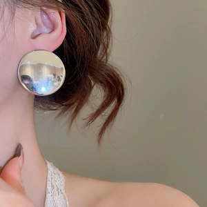 Vue de profil de grandes boucles d'oreilles fleurs en métal argenté poli portées par un mannequin