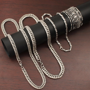 Detailed close-up of various stainless steel chain necklaces on a black display stand