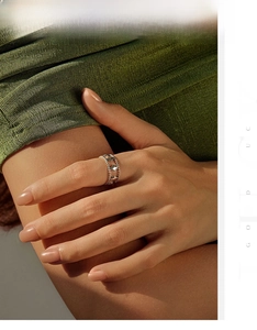Detail of silver rhombus openwork ring with beaded edges worn on a green fabric background