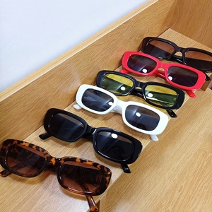 Close-up of retro rectangular sunglasses in various colors on a wooden display stand