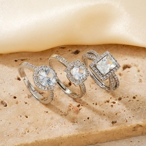 Three elegant adjustable copper rings with white cubic zirconia on beige stone and satin