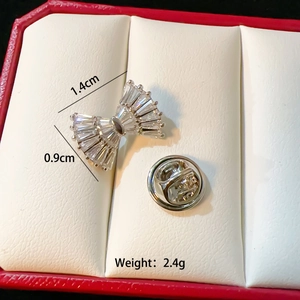 Macro shot of silver bow brooch with white zircons showing size 1.4cm by 0.9cm