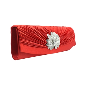 Detail view of red pleated satin evening clutch with sparkling rhinestone floral ornament