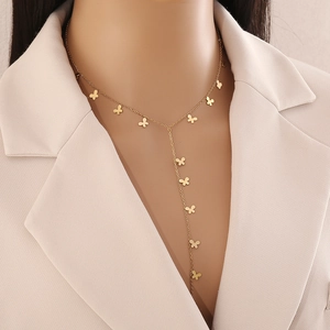 Détail d'un collier en Y avec pendentifs papillons dorés porté sur un tailleur beige