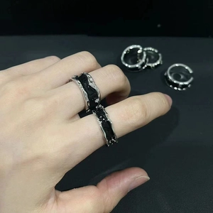 Detail of silver wavy rings with black enamel and zircons worn on the index finger