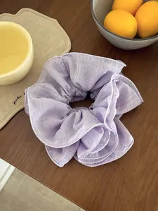 Detailed view of light purple checkered scrunchie with layered ruffles on wooden surface