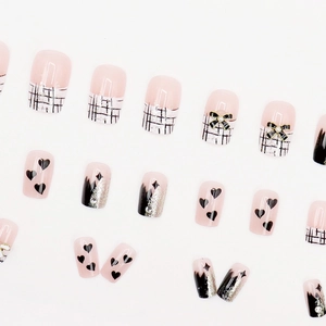 Pink and black press-on nail set featuring glitter, heart patterns, and 3D bow accents