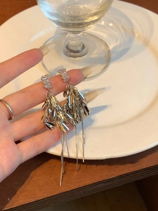 Détail de boucles d'oreilles pendantes argentées avec pompons et zircons cubiques