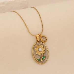 Détail d'un pendentif fleur doré avec perle et émail sur une chaîne serpent fine