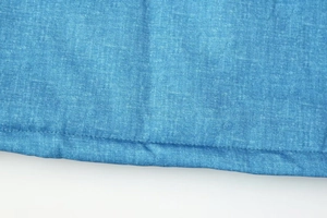 Detailaufnahme von blauem Denim-Stoff mit Doppelnaht am Saum und Köperbindungstextur