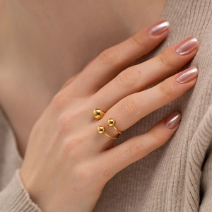 Bague ouverte plaquée or 18 carats avec trois sphères portée sur un tricot beige