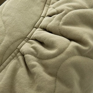 Vue détaillée de la texture matelassée et des coutures de la veste bomber vert olive