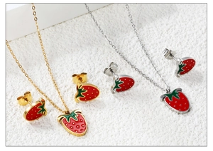 Detailed view of red strawberry necklaces and stud earrings set in gold and silver finish