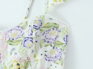 Détail d'une robe blanche à imprimé floral avec fines bretelles et décolleté festonné