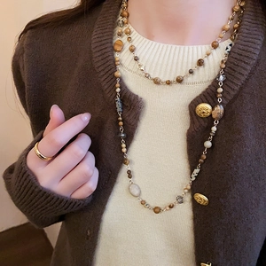 Detail of vintage beaded necklace with brown stones and leopard print beads on a model