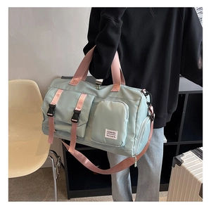 Detail of mint green travel bag with pink straps showing spacious pockets and logo