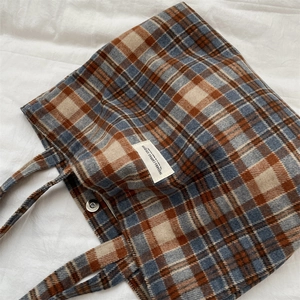Close-up of retro plaid canvas tote bag with magnetic clasp and woven label logo