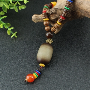 Ethnic wood beaded long necklace with oval stone pendant and red tassel on black texture