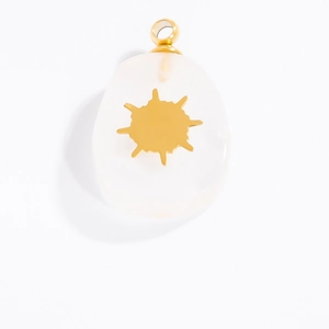 Detailed macro view of a golden sunburst pendant set in a translucent white gemstone