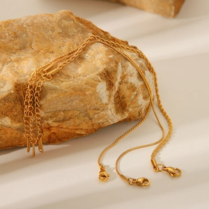Close-up of assorted gold stainless steel twisted and bead chains on a natural rock surface