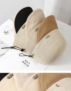 Close-up of straw sun hats in multiple colors featuring fine weave and adjustable cords