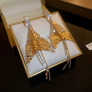 Macro shot of gold tassel earrings with rhinestone sequins on a jewelry display stand