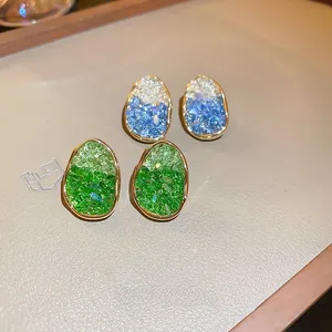 Detailed macro view of pebble-shaped gradient crystal stud earrings with gold metal edges