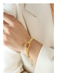 Detail shot of a gold-plated stainless steel curb link bracelet with a hollow heart charm
