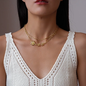 Collier doré double épaisseur avec pendentifs tournesol porté sur un haut en crochet blanc