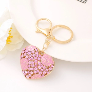 Detail of pink crystal heart keychain with rose enamel and gold plating on ceramic tray
