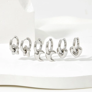 Detailed view of silver stainless steel hoop earrings with star, moon and heart charms