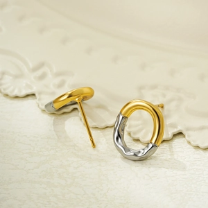 Close-up of two-tone 18K gold and silver stud earrings with fluid lava texture