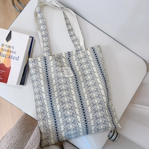Detailed top view of a cream canvas tote bag with blue retro floral print and logo label