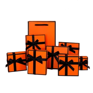 Elegant orange jewelry gift box set with black ribbon bow and matching paper tote bags