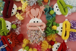 Detailed flat lay of handmade colorful crochet sausage mouth key covers in various colors